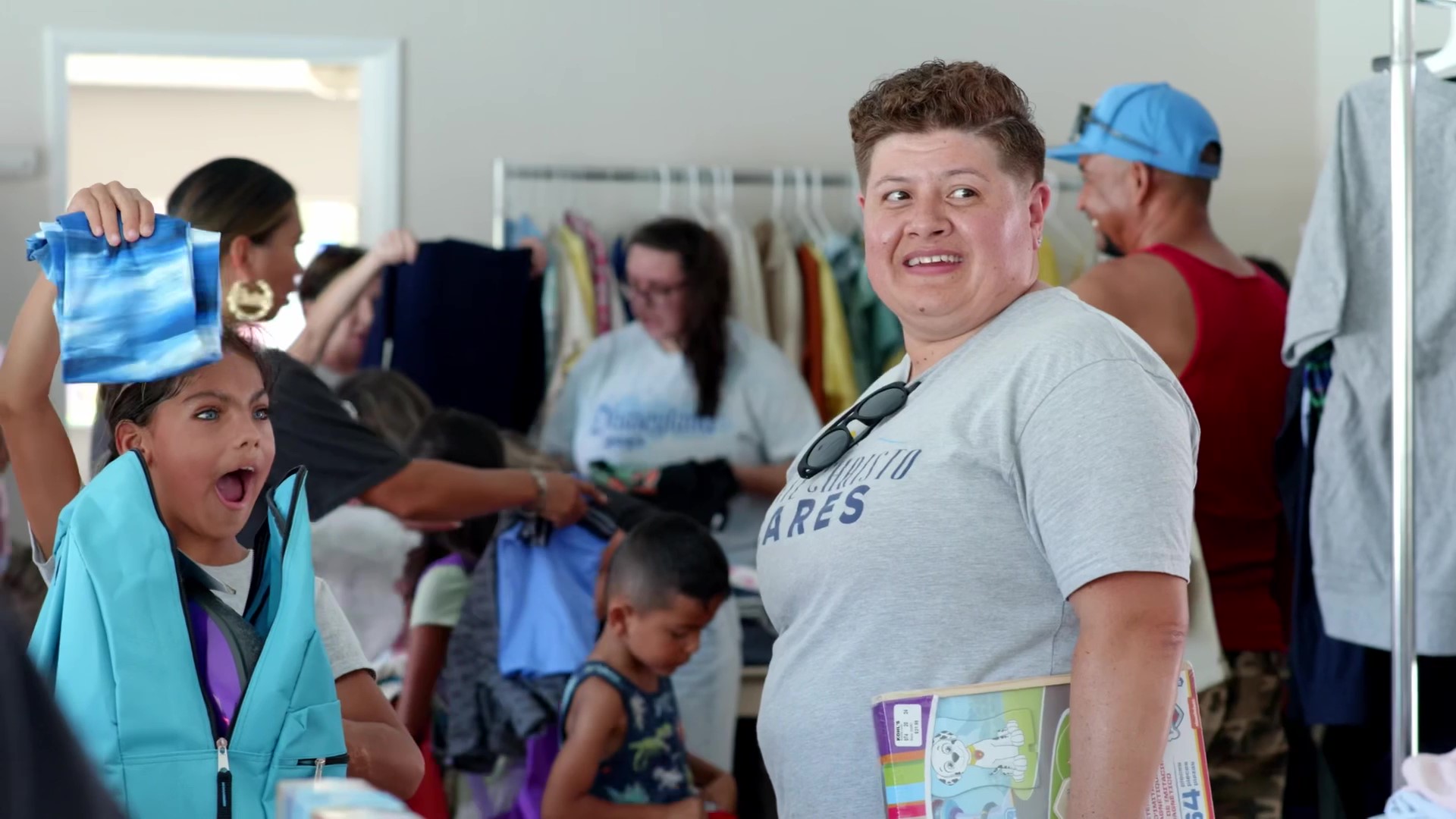 child excitedly holding new clothes with smiling volunteer